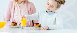 Child having a healthy breakfast, sitting with parent.